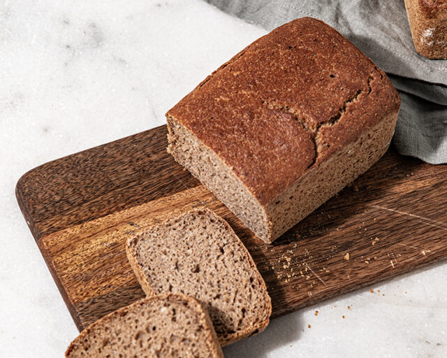 Das Bio Max Vollkornbrot ist ein Kastenbrot. Ein ganzes Brot liegt auf einem Tuch, einige Scheiben liegen davor.