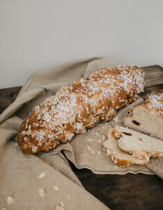 Man sieht einen großen Striegel auf einem beigen Tuch liegen. Er ist mit Hagelzucker rund Mandelblättchen bestreut.