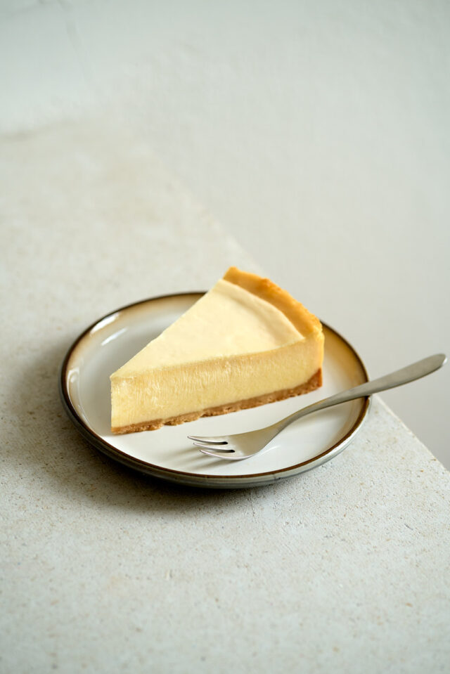 Ein Stück Cheesecake liegt auf einem hellen Teller.